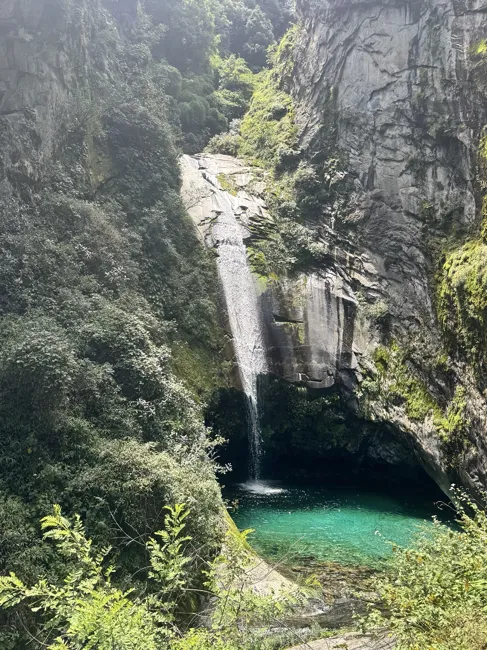 A waterfall drops into a clear turquoise pool.